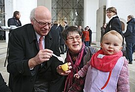 Bischof Gerhard Ulrich und Ehefrau Cornelia füttern Enkelin Paula (epd, Archiv, Februar 2013, Synodentagung Travemünde).
