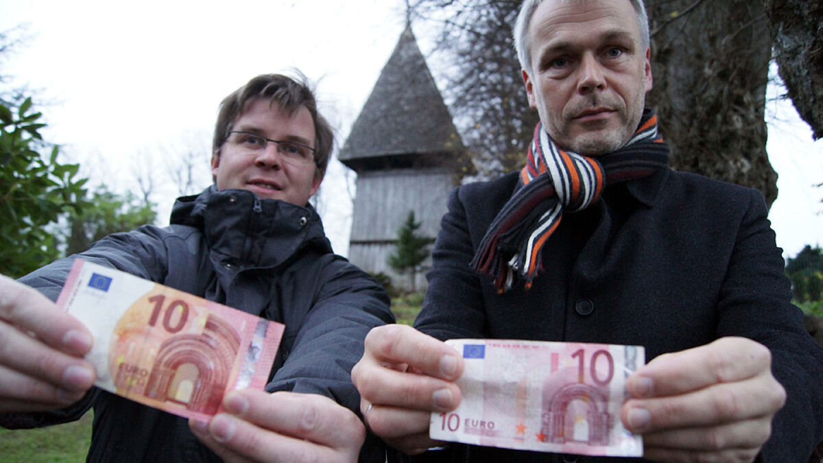 Zehn Euro Startkapital, präsentiert von Pastor Jörg Jackisch (li.) und Lutz Tschense, dem Vorsitzenden des Kirchbauvereins