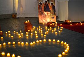 Kerzen formen ein Herz auf dem Boden einer Kirche.