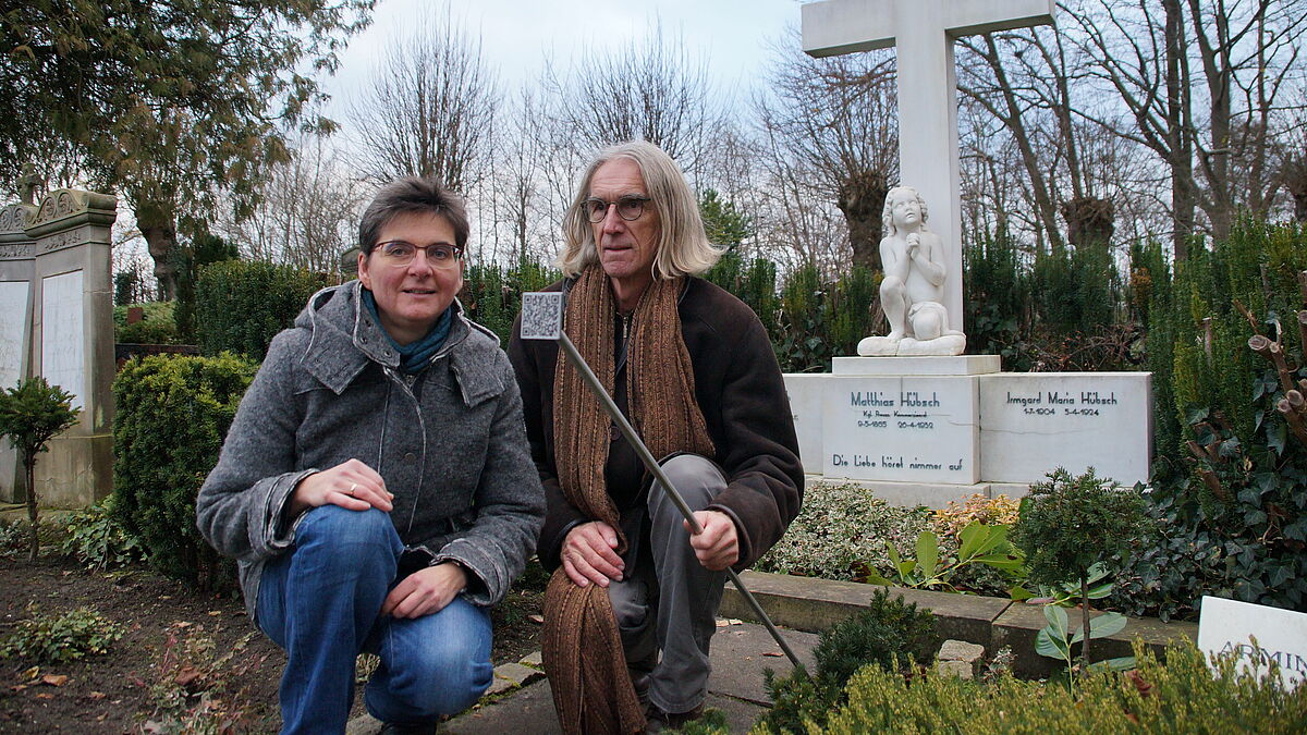 Pastorin Nadja Jöhnk und Historiker Nicolaus Schmidt zeigen die QR-Codes auf dem Friedhof in Arnis.