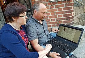 Doris to Baben und Lars Richter sitzen am Laptop und betrachten das neue Online-Tool.