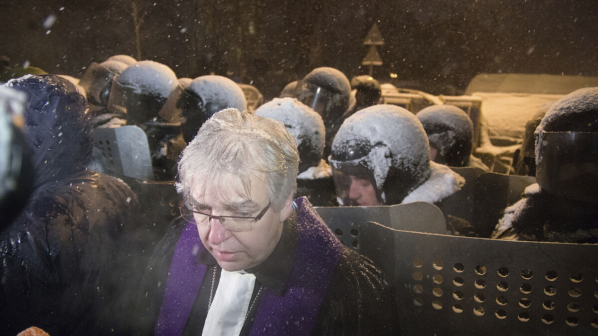 Pfarrer Ralf Haska in Kiew. Er steht vor einer Front von ukrainischen Polizisten.