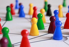 Spielfiguren aus Mensch Ärgere dich nicht stehen auf einem gezeichneten Netzwerk