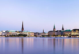 Kirchtürme und der Rathausturm spiegeln sich in der Alster.