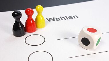Spielfiguren in Schwarz, Rot, Gold und Würfel 