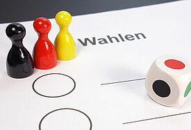 Spielfiguren in Schwarz, Rot, Gold und Würfel 