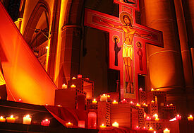 Von Kerzen erleuchtetes Taizé-Kreuz.