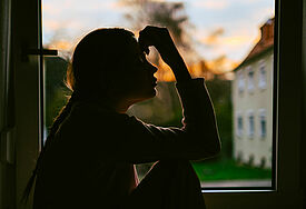 Frau am Fenster, die eine bedrückte Pose einnimmt